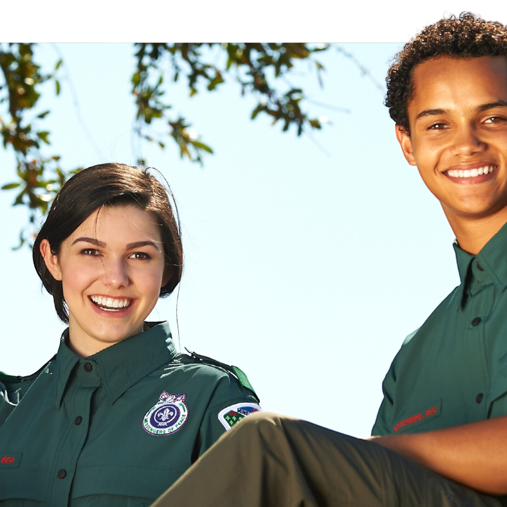 Two venture scouts sitting side by side smiling.