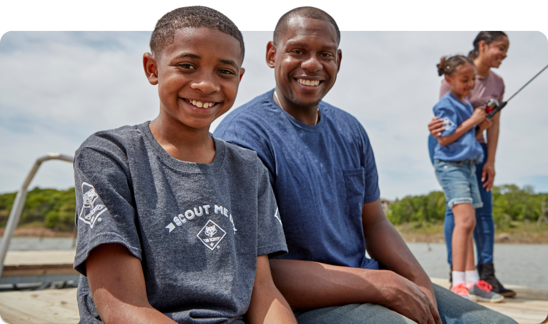 Father and cub scout son sitting side by side smiling